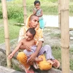 ছেঁড়া-মলিন শাড়ি পরা রেহানা খাতুন বাঁশের খুঁটির পাশে সন্তানদের নিয়ে বসে আছেন